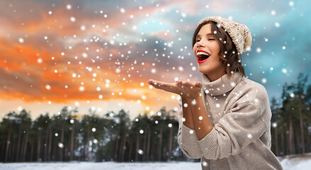 Image showing woman in hat sending air kiss over winter forest