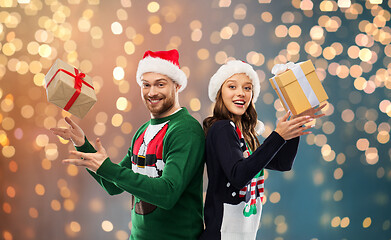 Image showing happy couple in christmas sweaters with gifts