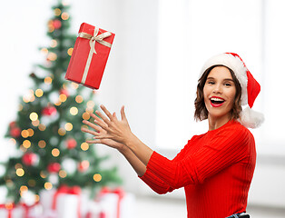 Image showing happy young woman in santa hat catching gift box