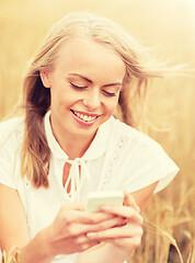 Image showing happy young woman with smartphone on cereal field