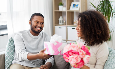 Image showing happy couple with flowers and gift at home