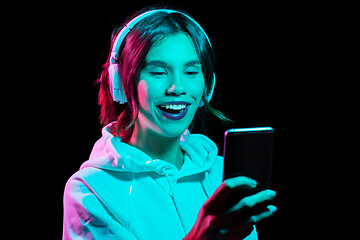 Image showing woman in headphones with smartphone in neon lights