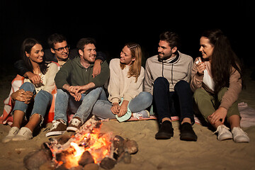 Image showing group of friends sitting at camp fire on beach