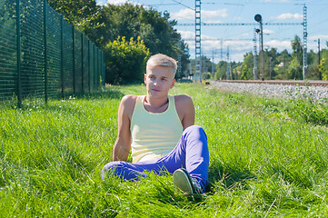 Image showing Young man in orange sitting on the green grass