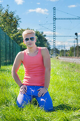 Image showing Young man in orange sitting on the green grass