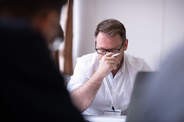 Image showing Business man writing notes while working on laptop