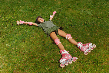 Image showing Teenage girl in a helmet learns to ride on roller skates outdoors