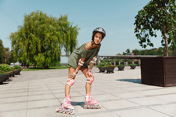 Image showing Teenage girl in a helmet learns to ride on roller skates outdoors