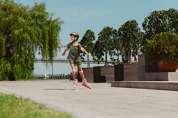 Image showing Teenage girl in a helmet learns to ride on roller skates outdoors