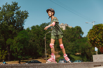 Image showing Teenage girl in a helmet learns to ride on roller skates outdoors