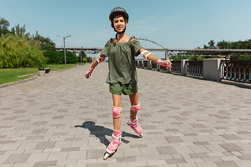 Image showing Teenage girl in a helmet learns to ride on roller skates outdoors