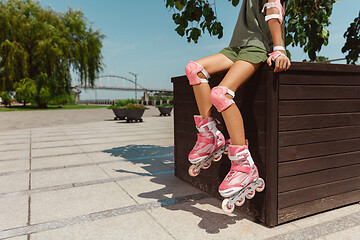 Image showing Teenage girl in a helmet learns to ride on roller skates outdoors