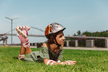 Image showing Teenage girl in a helmet learns to ride on roller skates outdoors