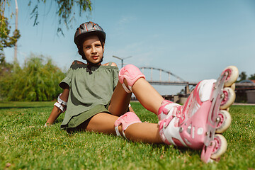 Image showing Teenage girl in a helmet learns to ride on roller skates outdoors