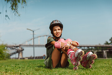 Image showing Teenage girl in a helmet learns to ride on roller skates outdoors