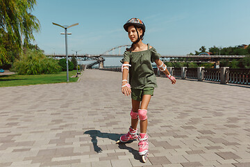 Image showing Teenage girl in a helmet learns to ride on roller skates outdoors