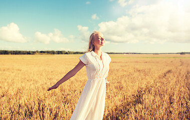 Image showing smiling young woman in white dress on cereal field