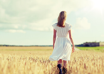 Image showing young woman in white dress walking along on field