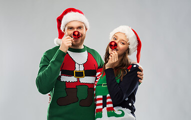 Image showing happy couple in christmas sweaters and santa hats