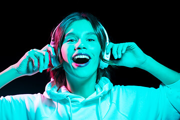 Image showing woman in headphones listening to music in neon