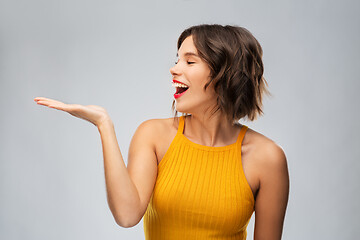 Image showing happy young woman holding something on empty hand