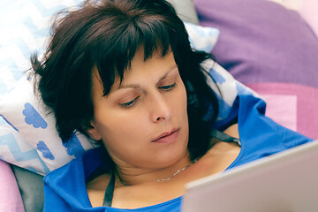 Image showing Middle age woman resting in bed with tablet