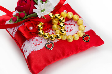 Image showing pillow with golden beads bracelet rings 