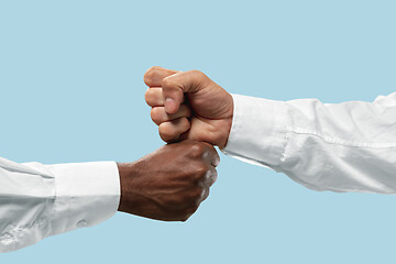 Image showing Two male hands competion in arm wrestling isolated on blue studio background