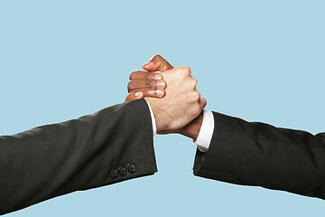 Image showing Two male hands shaking isolated on blue studio background