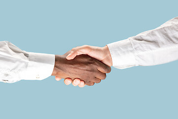 Image showing Two male hands shaking isolated on blue studio background