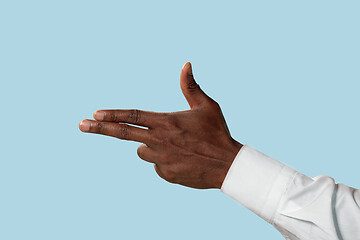 Image showing Male hand demonstrating a gesture of gun isolated on blue background