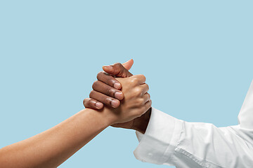 Image showing Two male hands competion in arm wrestling isolated on blue studio background