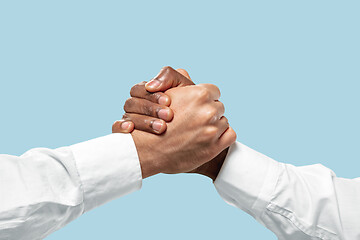 Image showing Two male hands competion in arm wrestling isolated on blue studio background