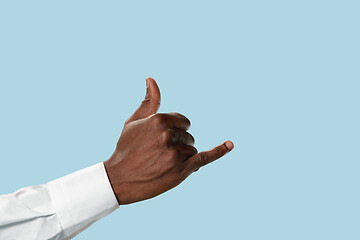 Image showing Male hand demonstrating a gesture CALL ME isolated on blue background