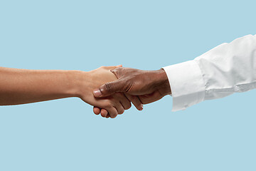 Image showing Two male hands shaking isolated on blue studio background