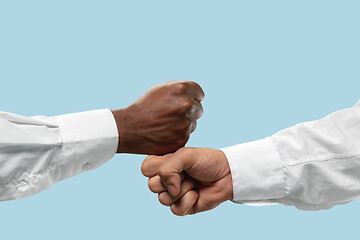 Image showing Two male hands competion in arm wrestling isolated on blue studio background