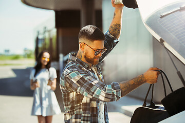 Image showing Young couple preparing for vacation trip on the car in sunny day