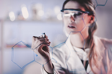 Image showing Portrait of a confident female researcher in life science laboratory writing structural chemical formula on a glass board.