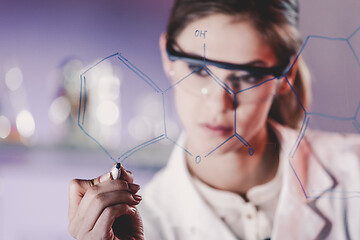 Image showing Portrait of a confident female researcher in life science laboratory writing structural chemical formula on a glass board.