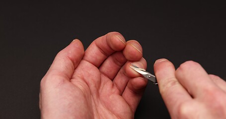 Image showing Man cuts fingernail for himself
