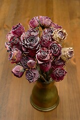 Image showing a bouquet of dry roses in a copper coffee turk on a wooden backg