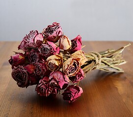 Image showing bouquet of dried roses on a wooden table