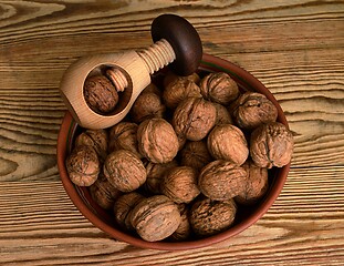 Image showing walnuts in a bowl and a wooden nutcracker on a wooden backdrop