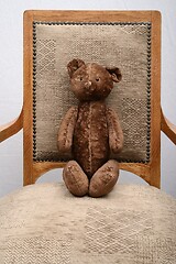 Image showing shabby teddy bear sitting in an old vintage armchair