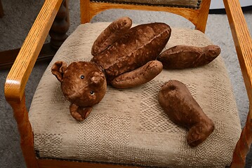 Image showing broken teddy bear toy with severed paws on an old armchair