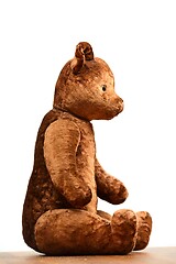 Image showing shabby teddy bear toy sits sideways on a white 