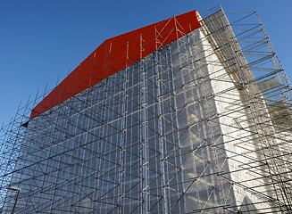 Image showing building in scaffolding during renovation against blue sky 