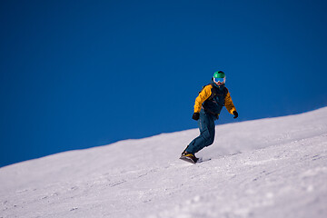 Image showing snowboarder running down the slope and ride free style