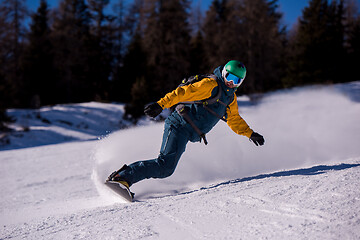 Image showing snowboarder running down the slope and ride free style