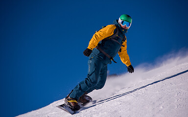 Image showing snowboarder running down the slope and ride free style